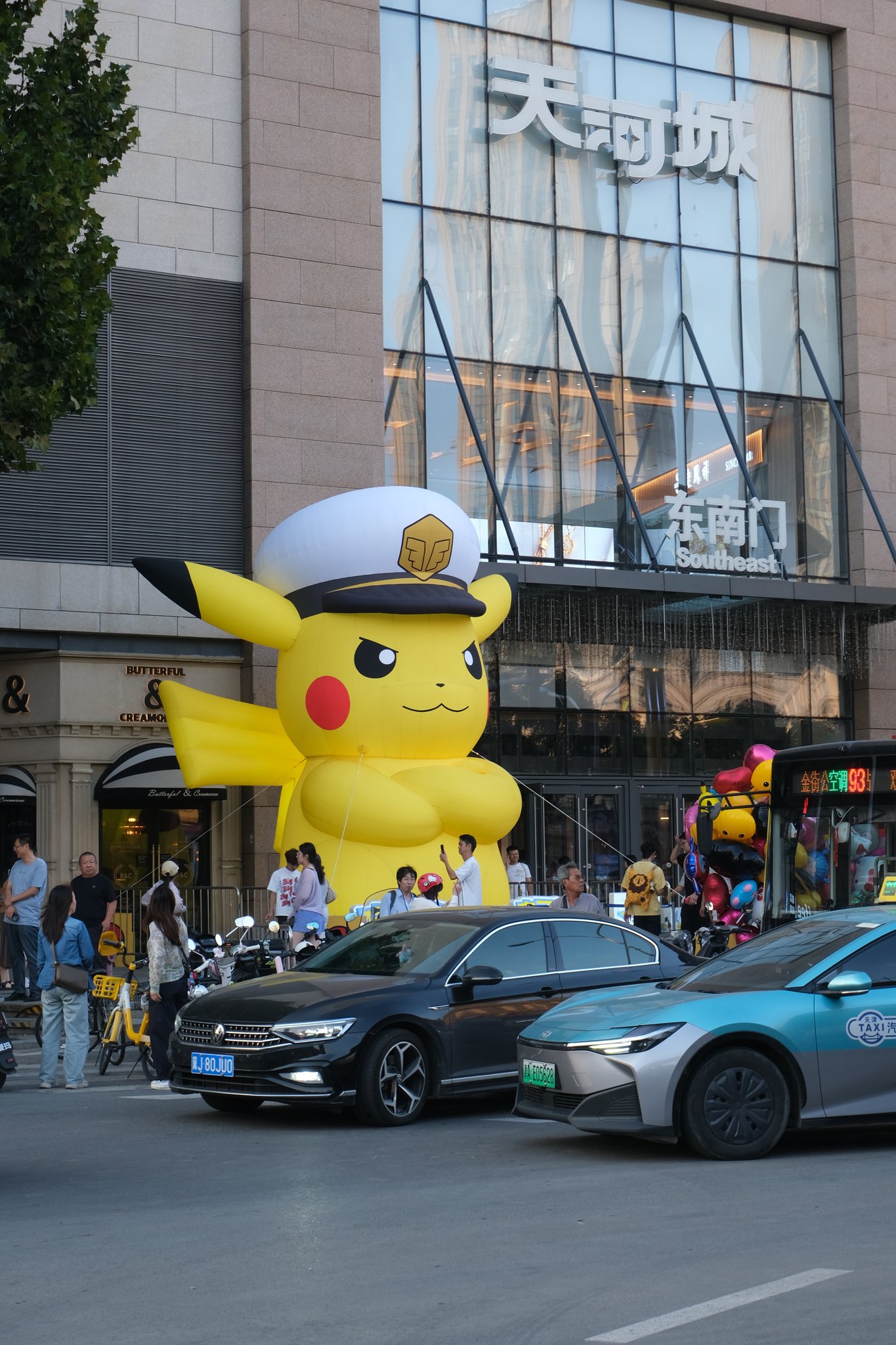 帽子をかぶった大きなピカチュウが通りに立つ