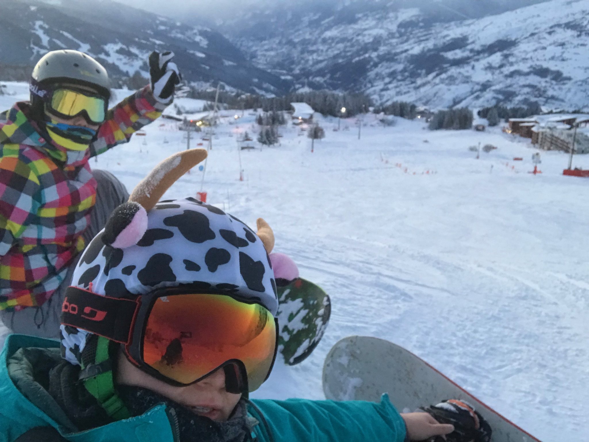 Deux personnes casquées prennent une photo ensemble sur une piste enneigée