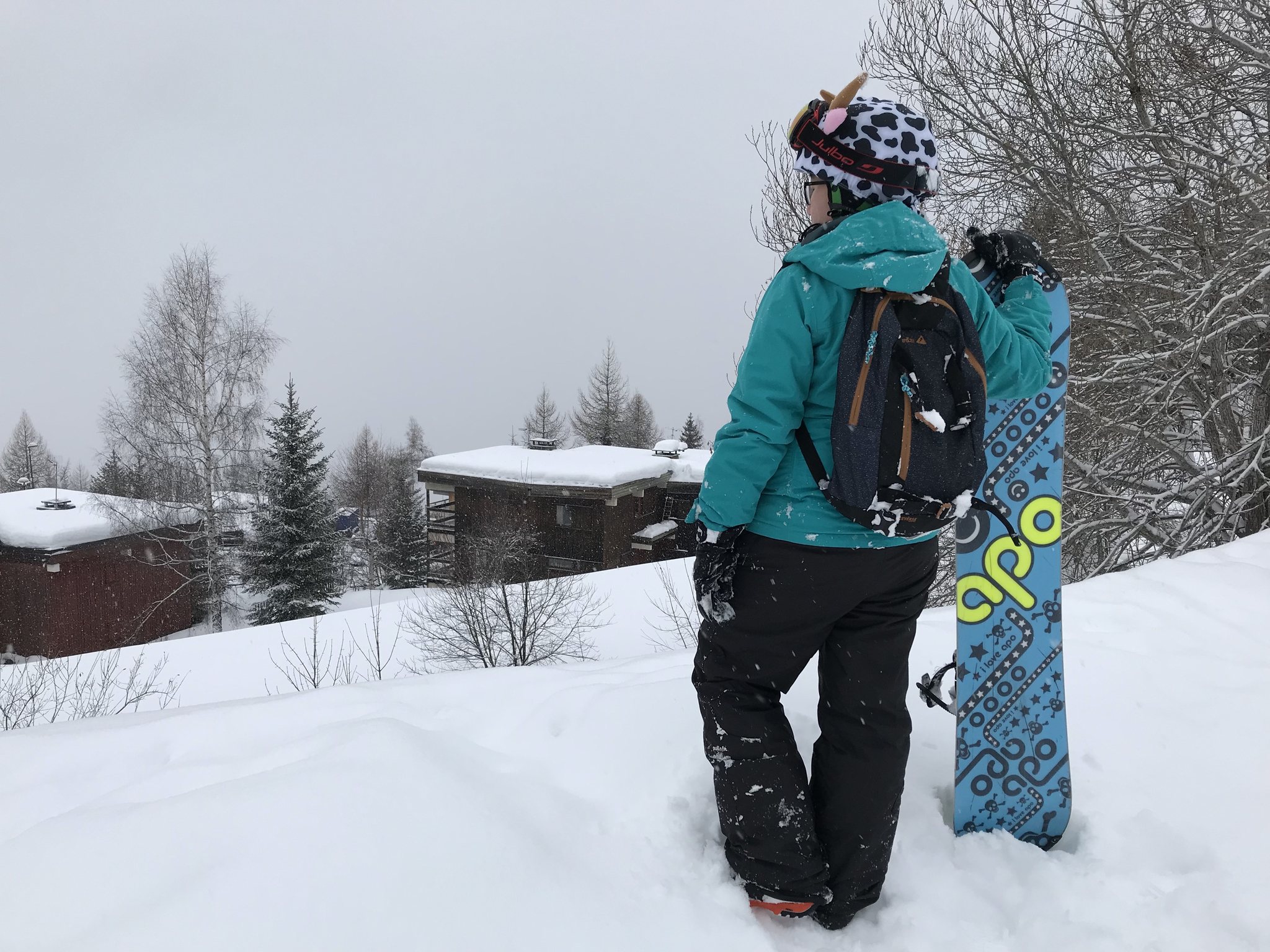 Une personne portant un snowboard se tient sur une pente enneigée